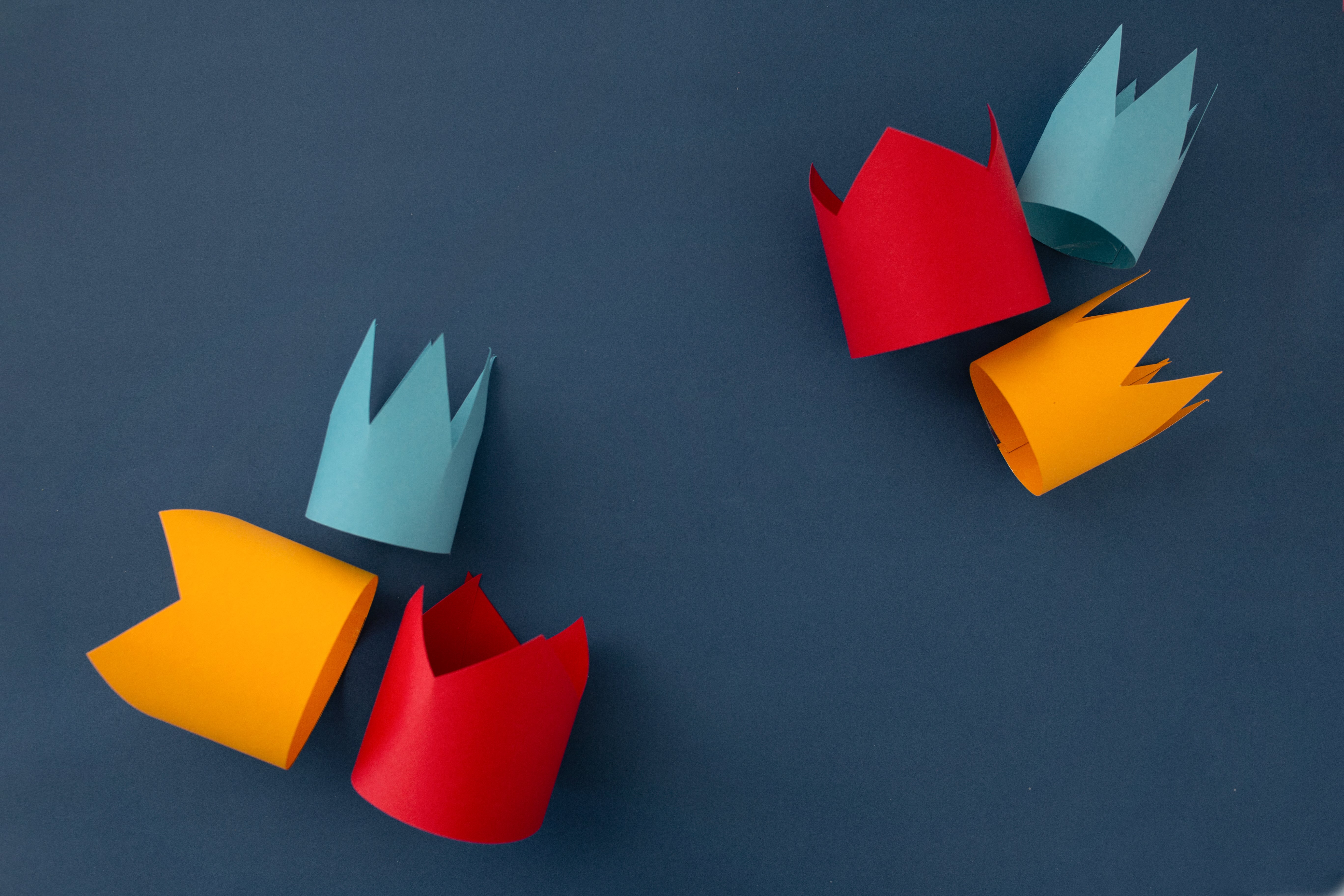 Colorful paper crowns on a blue background representing creativity and brand building