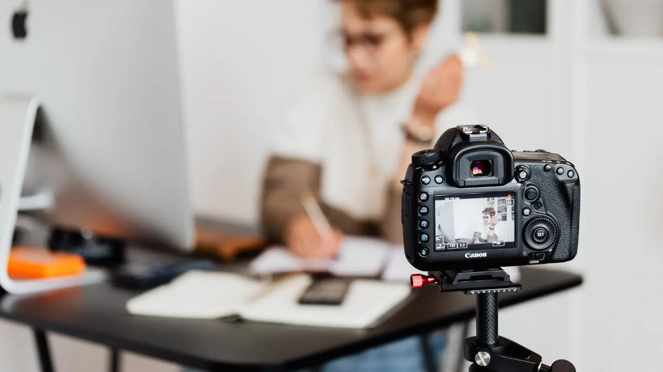 Camera set up to record a creator working at a desk, showing behind the scenes video content creation