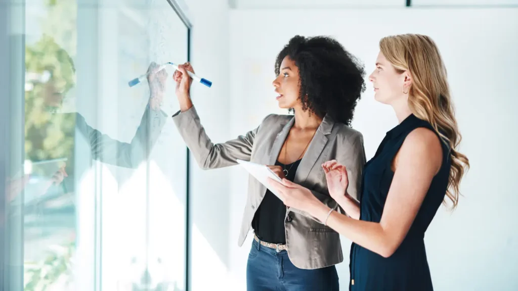 Two marketing professionals developing a purpose-driven brand narrative on a glass board during a strategic storytelling planning session