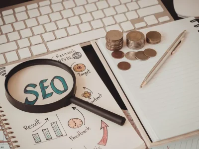 Ethical SEO planning workspace with a magnifying glass highlighting SEO, notebooks showing research and results, coins symbolizing sustainable growth, and a keyboard representing transparent digital strategy.
