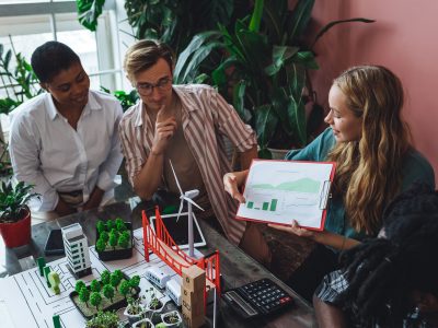 Diverse professionals reviewing sustainability data and urban planning models, discussing measurable environmental impact and long-term business strategy.